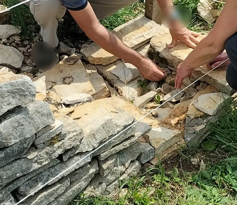 Hände beim Errichten einer Trockenmauer